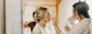 person applying lipgloss to bride