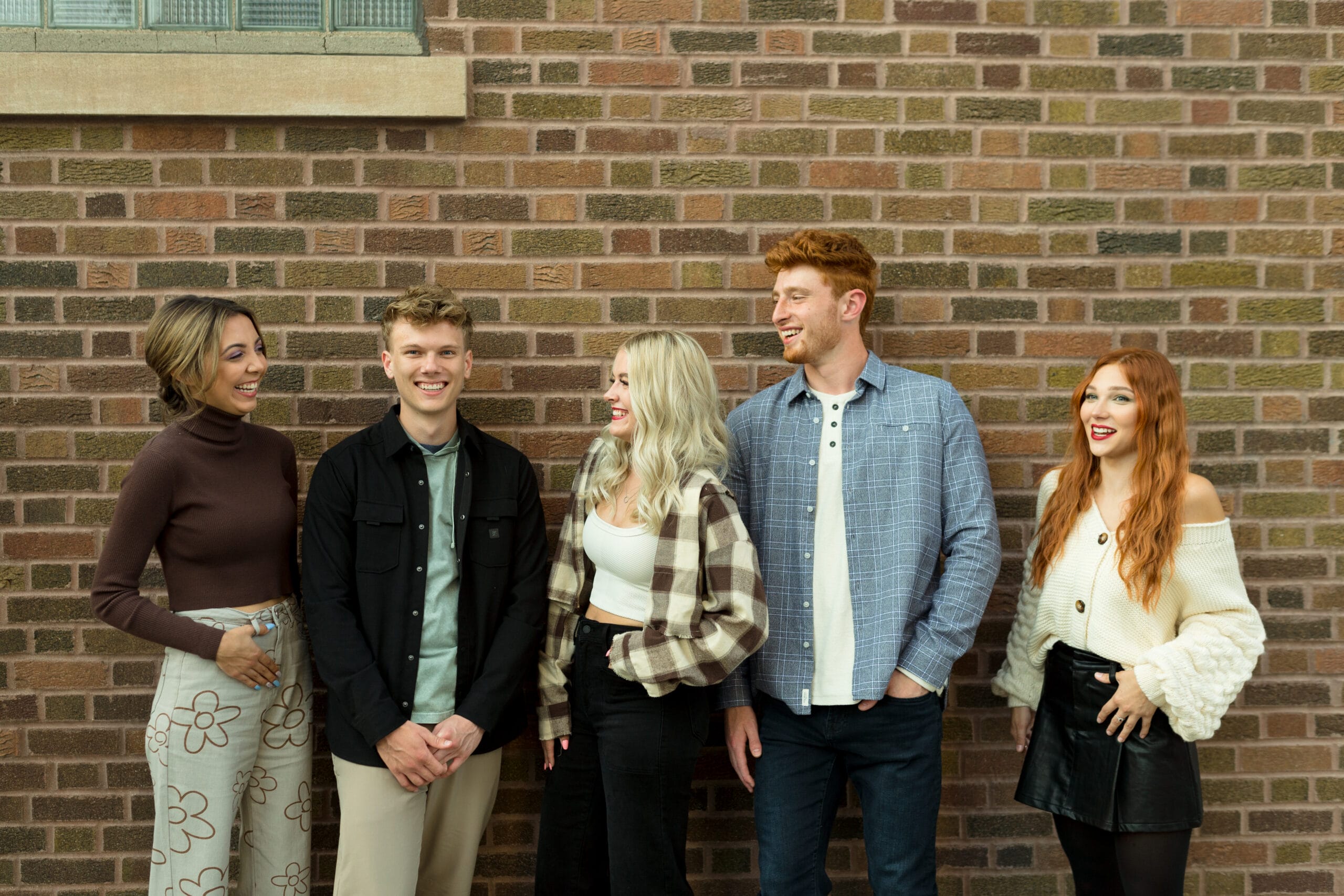 people smiling in front of brick wall
