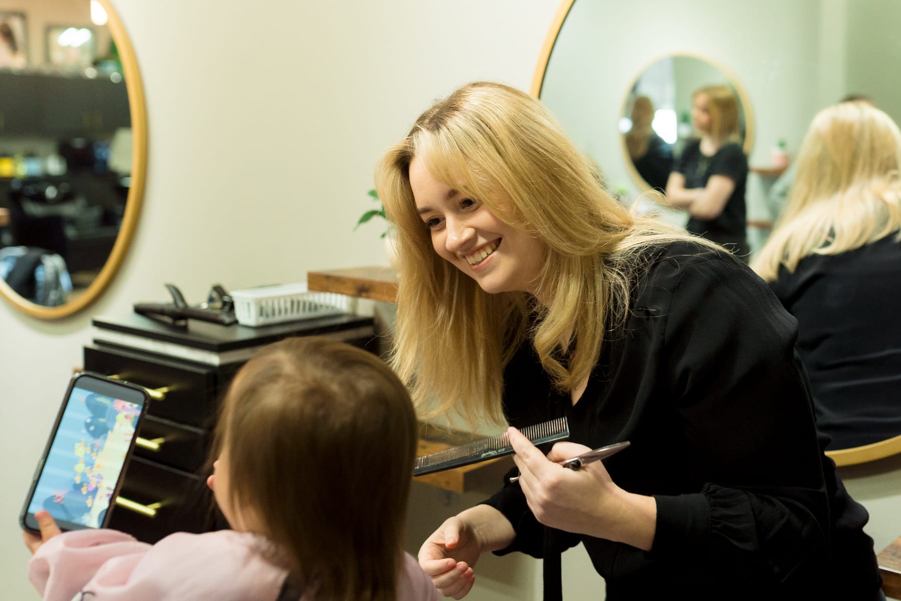 stylist smiling while cutting child's hair